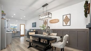 A modern kitchen with a dining area, featuring a wooden table, bench seating, and pendant lighting. - Paso Robles Retreat - Newly Remodeled- (Paso Robles)