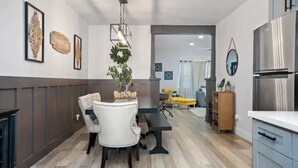 A modern kitchen with a dining area, featuring a wooden table, chairs, and a hanging light fixture. - Paso Robles Retreat - Newly Remodeled- (Paso Robles)