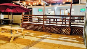 An outdoor seating area with a wooden table and chairs, a red umbrella, and string lights. - Paso Robles Retreat - Newly Remodeled- (Paso Robles)