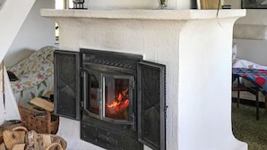 A fireplace with a fire burning inside, set in a white stone structure. - Beautiful home in Nybrostrand with WiFi (Nybrostrand)