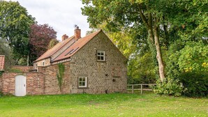Een stenen huis met een pannendak, een bakstenen muur en een witte deur.