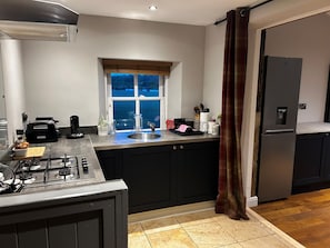 A modern kitchen with a gas stove, a sink, a window, and a refrigerator.