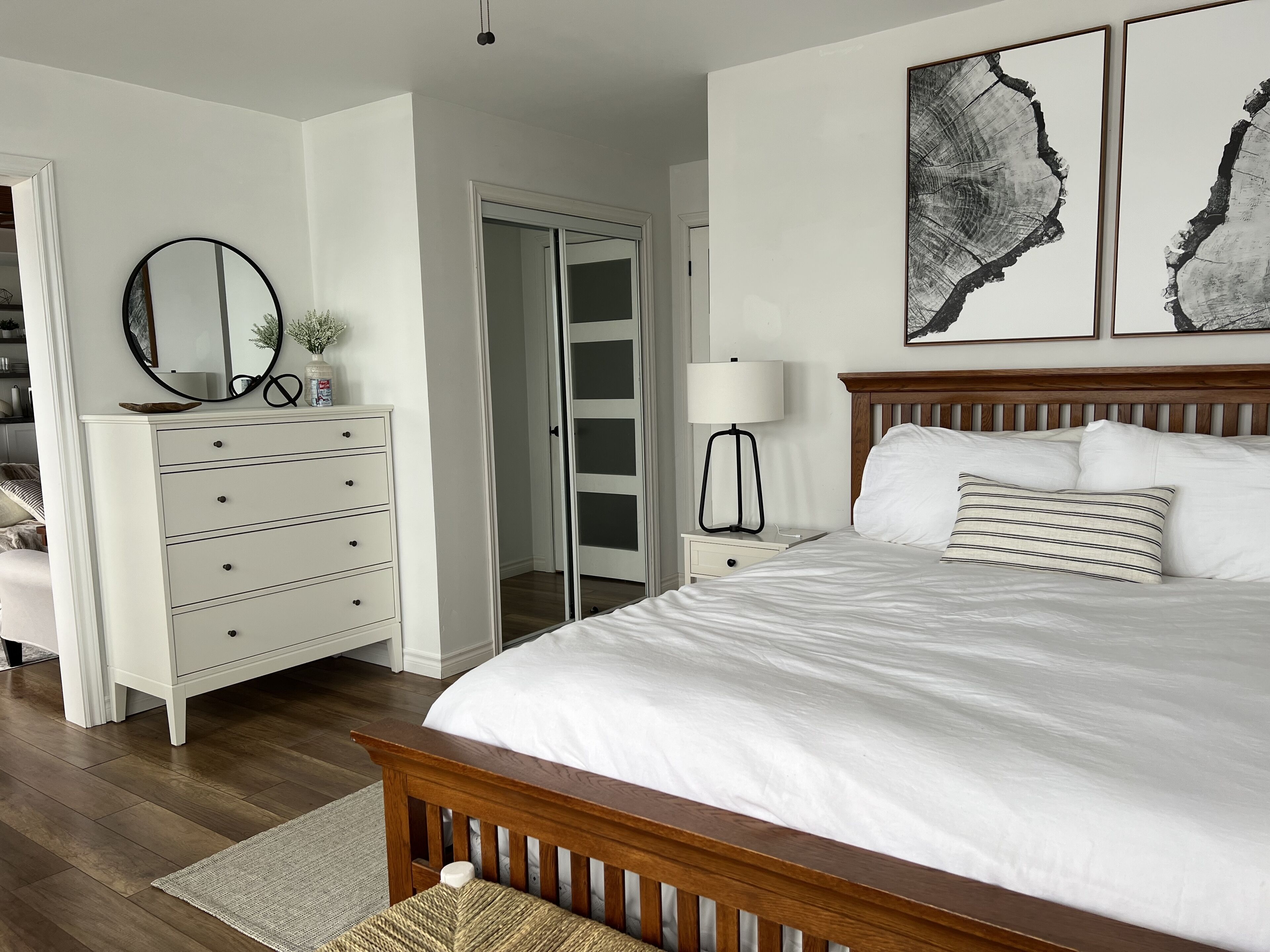 A bedroom with a wooden bed, white dresser, and a walk-in closet.