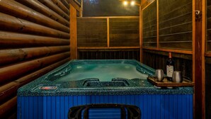 Interior de una cabaña de madera con un jacuzzi, paredes de madera y una ventana.