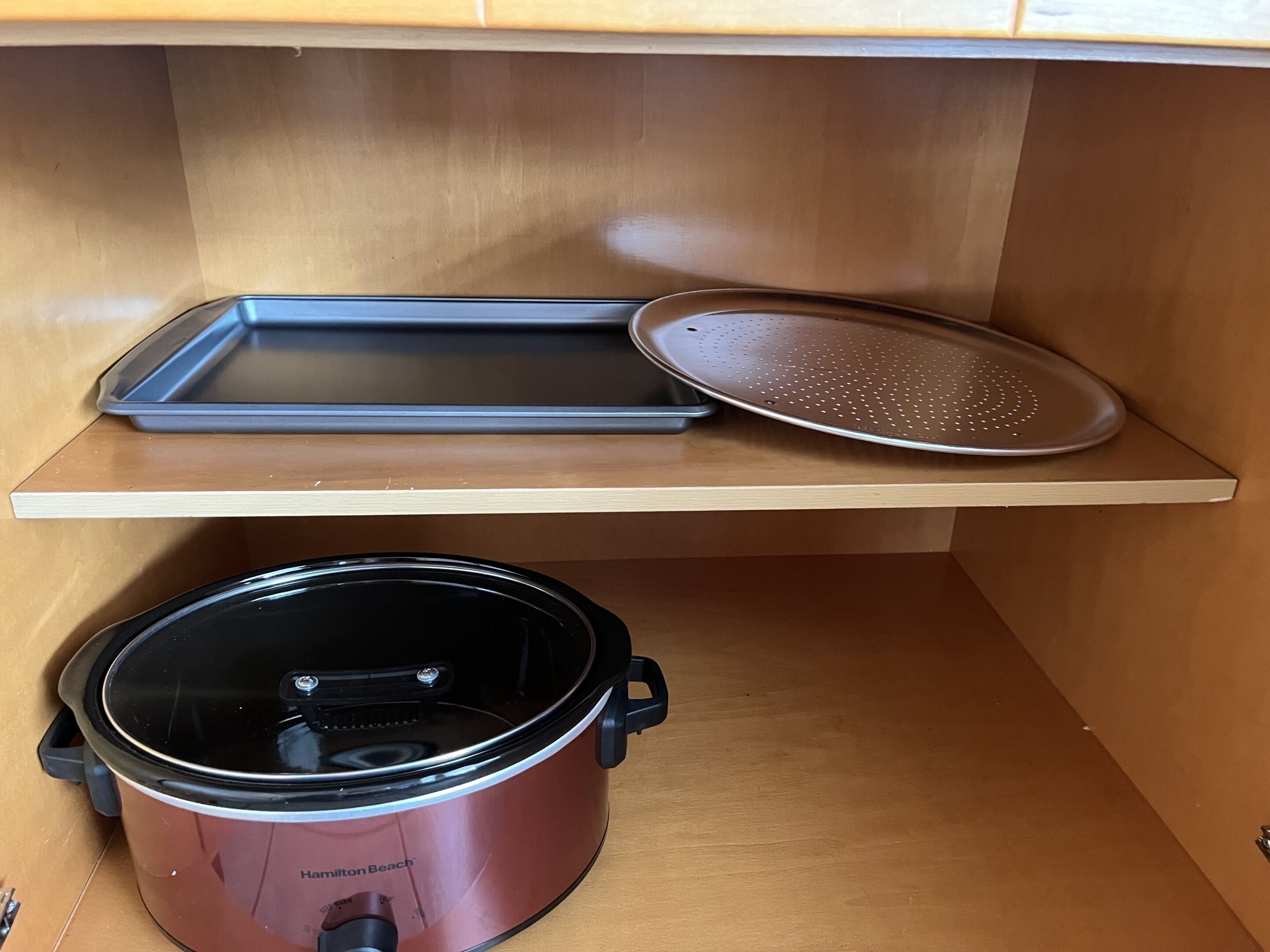 A kitchen with a countertop, a slow cooker, and a baking tray.