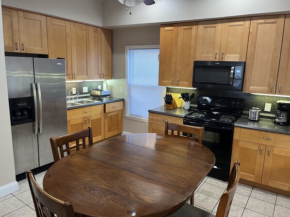 A modern kitchen with wooden cabinets, stainless steel appliances, and a dining table.