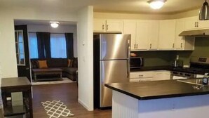 A modern kitchen with white cabinets, a stainless steel refrigerator, and a microwave. - Quiet Private Country Cottage (Riverton)
