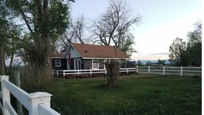 A rural house with a white fence, surrounded by trees and open fields. - Quiet Private Country Cottage (Riverton)