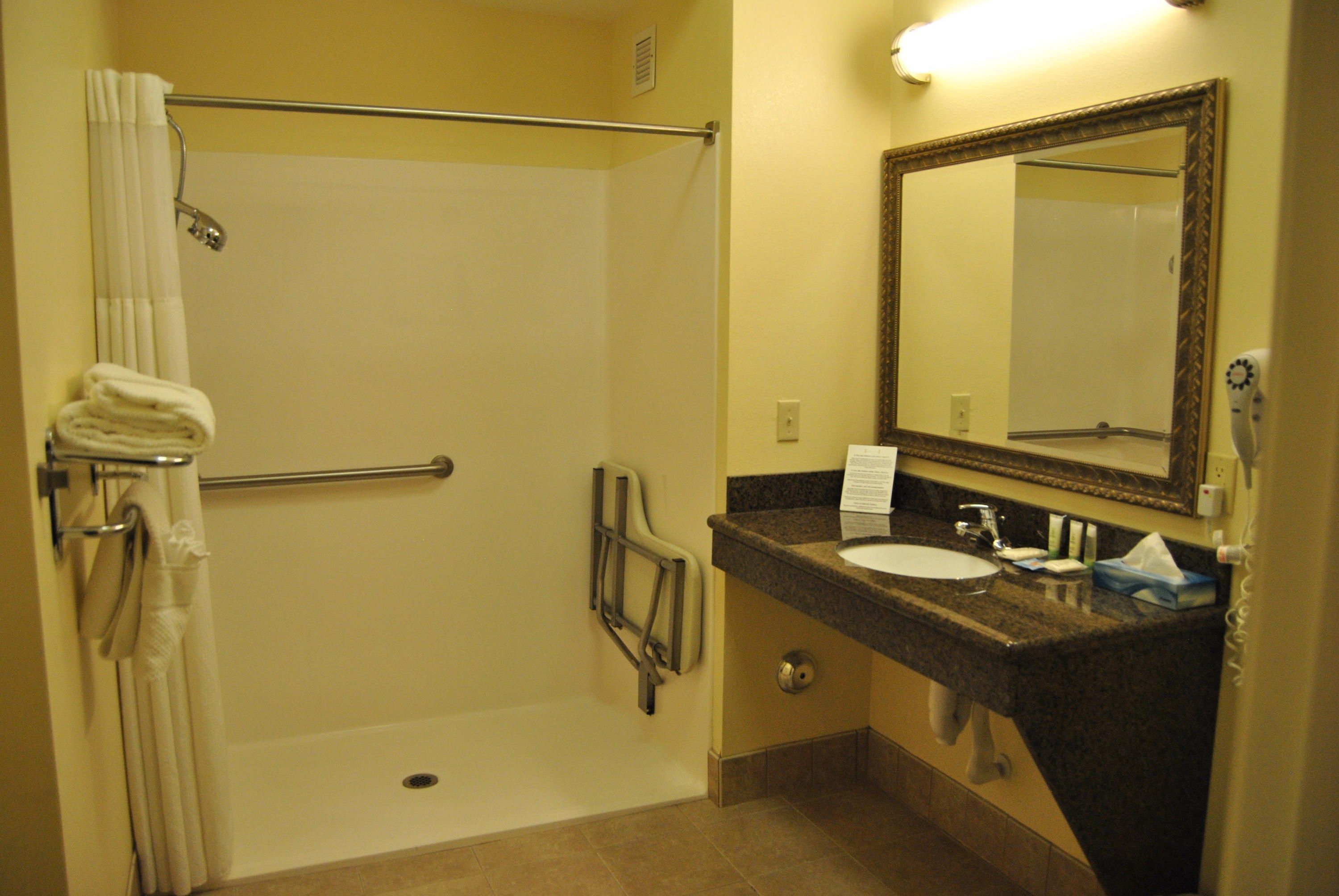 A bathroom with a shower, a sink, a mirror, and a towel rack.