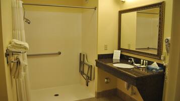 A bathroom with a shower, a sink, a mirror, and a towel rack.