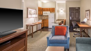 A compact living space with a TV, seating area, kitchenette, and a door.