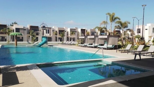 A swimming pool with a slide, lounge chairs, and palm trees. - CASA VELA by TRVL2HM (Nuevo Nayarit)
