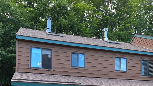 Un bâtiment à deux étages doté d’un porche, de drapeaux américains et d’une pile de bois de chauffage.