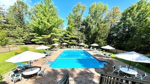 A rectangular swimming pool with a brick deck, surrounded by lawn chairs and umbrellas. - Enjoy Fall Foliage in Renov End Unit Townhouse with Fireplace (Dover)