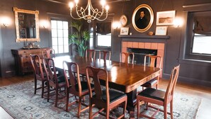 A dining room with a large wooden table, eight chairs, a chandelier, and a fireplace. - Main Residence: 5 beds, 5 baths, sleeping porches, & full kitchen. (Medford)