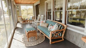 A covered porch with wicker furniture, a striped sofa, and a view of the outdoors. - Main Residence: 5 beds, 5 baths, sleeping porches, & full kitchen. (Medford)