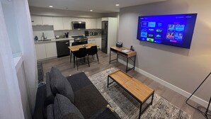 A modern living room with a sofa, a coffee table, and a TV mounted on the wall displaying streaming services.