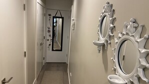 A hallway with a patterned floor, a door with a mirror, and wall-mounted sinks.