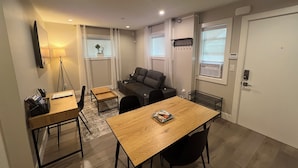 A modern living room with a sofa, a dining table, and a small kitchen area.