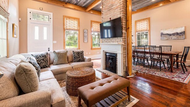 A spacious living room with a large sectional sofa, a fireplace, a dining area with a wooden table and chairs, and a ceiling fan. - "Life of Riley" 3bd/3ba Irish Channel Home! (New Orleans)