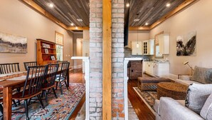 A spacious living area with a dining table, chairs, a sofa, and a kitchen in the background. - "Life of Riley" 3bd/3ba Irish Channel Home! (New Orleans)