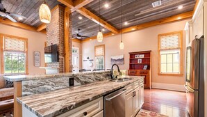 A spacious kitchen with a marble countertop, wooden beams, and a large island. - "Life of Riley" 3bd/3ba Irish Channel Home! (New Orleans)