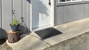 A house with a white door, a window, and a hanging planter. - Serene Studio overlooking the river (Juneau)