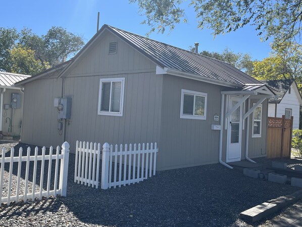 A small, single-story building with a white picket fence, a small porch, and a gravel driveway. - Cheerful historic Townsend Park bungalow in the heart of downtown!
(Montrose)