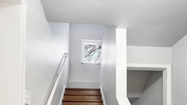 A wooden staircase with white railings and a dark carpeted landing. - Downtown Wyandotte, Clean and Cozy! (Wyandotte)