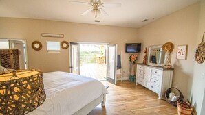 Une chambre à coucher avec un lit, une commode, un téléviseur et un balcon.