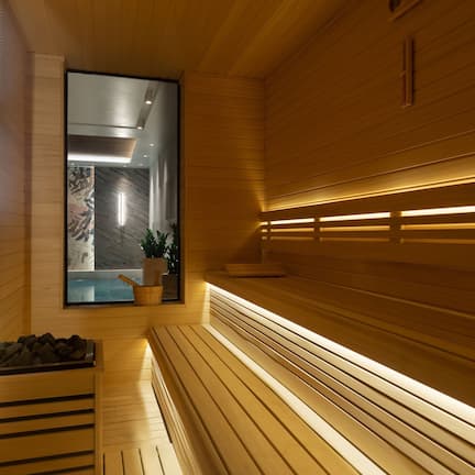 A modern sauna with wooden benches and a glass wall.
