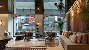 A modern lounge area with a sofa, armchairs, and a coffee table. Large windows provide views of the street. - Burdock Hotel Istanbul, Autograph Collection (Istanbul)