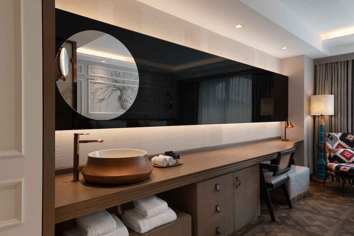 A modern bathroom with a large mirror, a round sink, and a vanity with storage.
