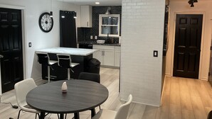 A modern kitchen with a black and white color scheme, a round dining table, and a clock on the wall. - Tuxedo Touch Modern 2BR Townhouse (Smyrna)