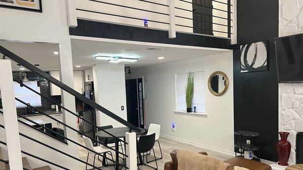 A modern living room with a staircase, a dining area, and a kitchen. - Tuxedo Touch Modern 2BR Townhouse (Smyrna)