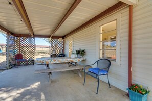 A covered patio area with a wooden table and chairs, a lattice fence, and a potted plant. - Charming Subiaco Getaway Near Arkansas River! (Subiaco)