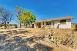 A single-story house with a front porch, a small garden with rocks and plants, and a clear blue sky. - Charming Subiaco Getaway Near Arkansas River! (Subiaco)