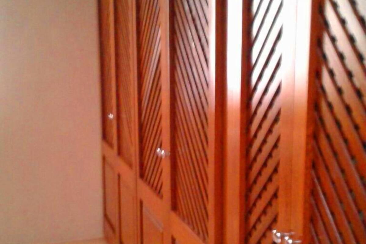 A room with a wooden wardrobe and a plain wall.