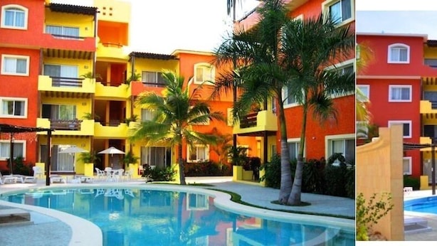 Un hotel con edificios coloridos, piscina y palmeras.