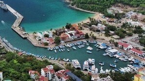 A coastal town with a marina, buildings, and a lighthouse.