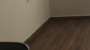 A room with a flat-screen TV mounted on the wall, a dark wooden floor, and a plain white wall.
