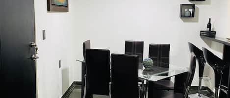 A dining area with a table and chairs, an air conditioning unit, and a door.