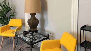 Una habitación con dos sillas amarillas, una mesa con lámpara y una planta.