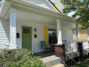 A white house with a green door, a yellow door, and a porch with a chair. - Apt A The Yellow Shuttered House (Sharon)