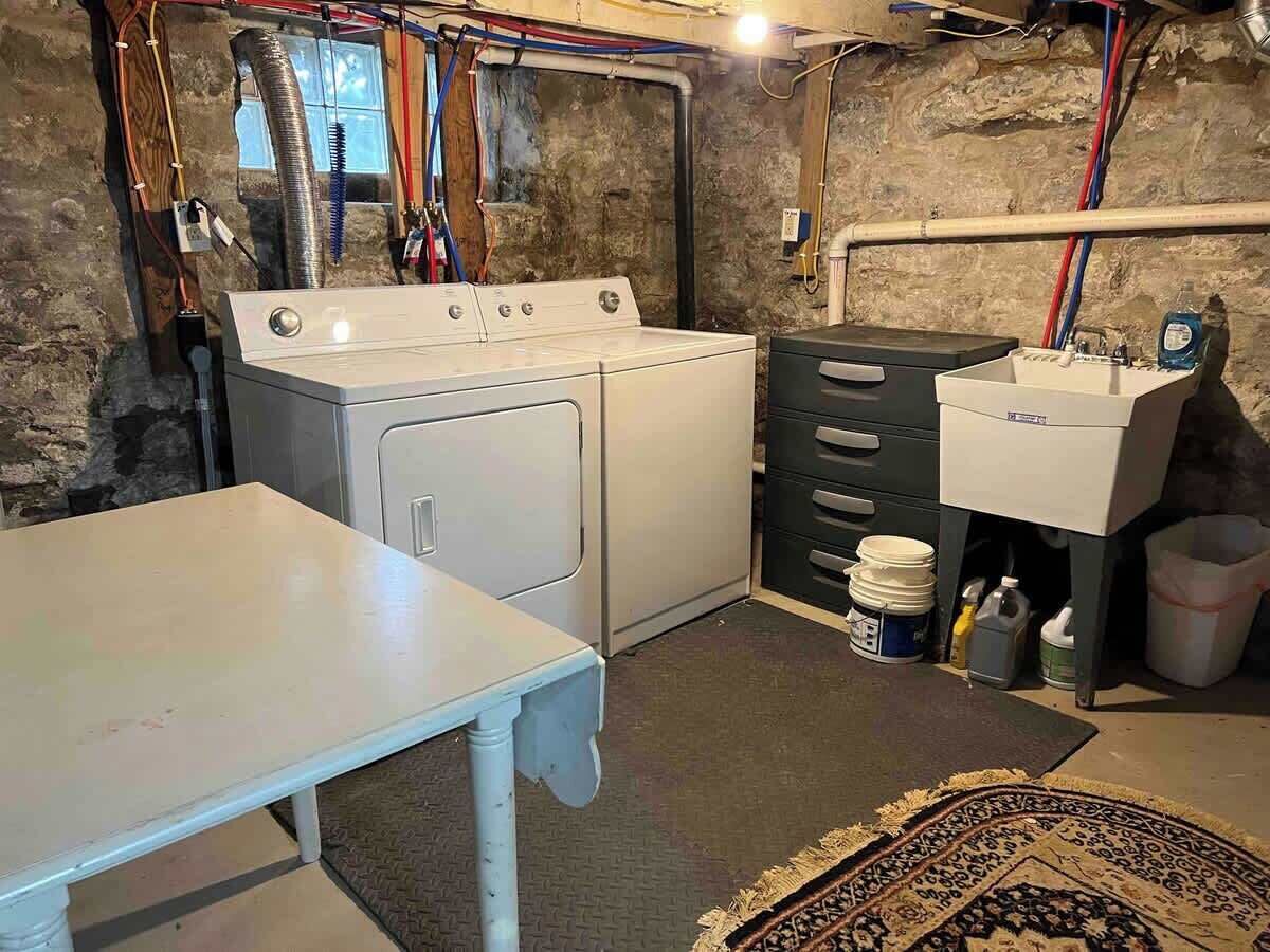 A laundry room with a washing machine, dryer, sink, and storage cabinets.