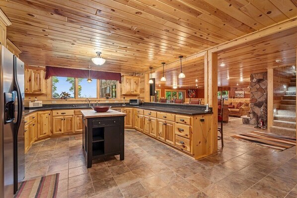 A spacious kitchen with wooden cabinets, a central island, and a stone accent wall.