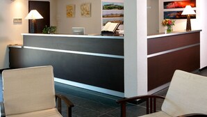 A reception area with a counter, two chairs, and artwork on the walls.