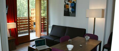 A modern room with a sofa, a dining table, and a laptop.