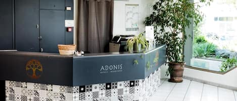 A reception desk with a tree logo, a potted plant, and a view of the outdoors.