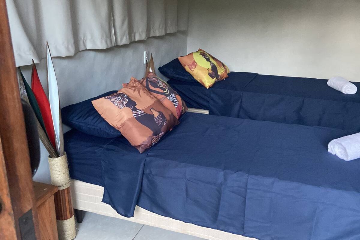 Un lit simple avec une literie bleue, un oreiller marron à motifs et une serviette blanche.